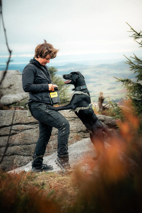 Psí trenérka na výšlapu se svým psem, dávající Dogule psí pamlsek