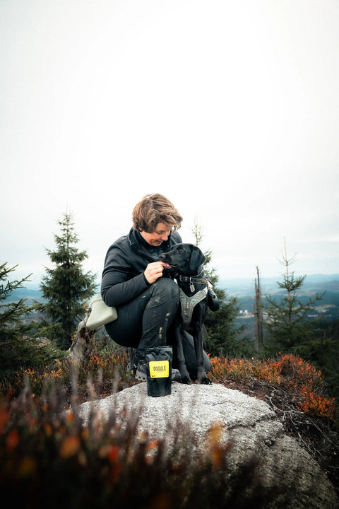 Psí trenérka na výšlapu se svým psem, dávající Dogule psí pamlsek
